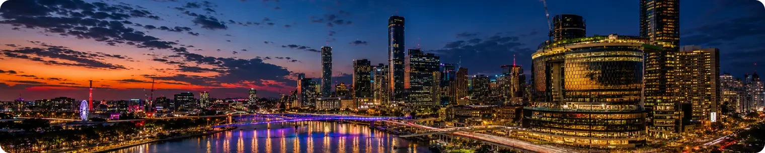 Evening view of Brisbanes riverside skyline with illuminated buildings bridges traffic lights and reflections on the river